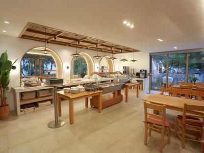 Modernes Hotelrestaurant mit Holzmöbeln, Buffet und großen Fenstern zur Gartenseite.