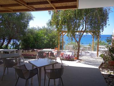 Sonnige Terrassenbereich mit Sitzgelegenheiten und Blick aufs Meer in einem Hotel.