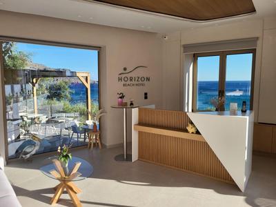 Moderner Hotel-Loungebereich mit Meerblick und Holzbank neben großen Fenstern und Außenterrasse.