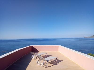 Dachterrasse mit zwei Liegestühlen und Tisch mit Meerblick unter klarem Himmel.