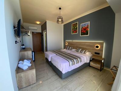 Modern eingerichtetes Hotelzimmer mit Doppelbett, Fernseher und Nachttischen.