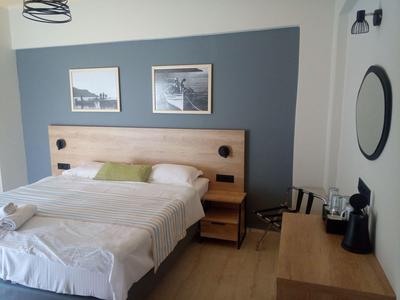 Modernes Hotelzimmer mit Doppelbett, zwei Nachttischen und einem Schreibtisch mit Kaffeemaschine.