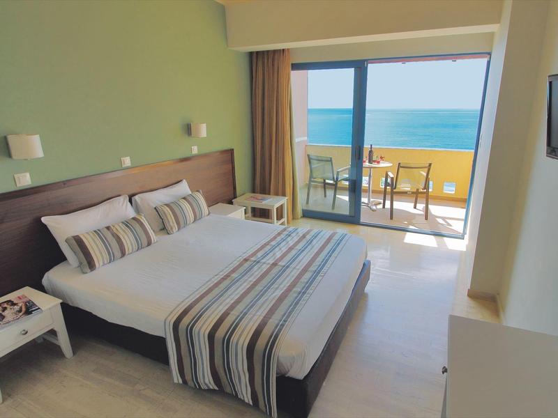 Modern hotelkamer met tweepersoonsbed, balkon en zeezicht.