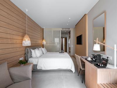 Modernes Hotelzimmer mit Doppelbett, Schreibtisch und Sitzbereich in neutralen Farbtönen.