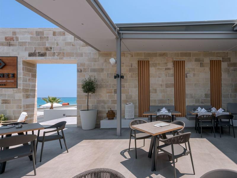 Nowoczesny zewnętrzny obszar hotelu z stołami, krzesłami i widokiem na morze.