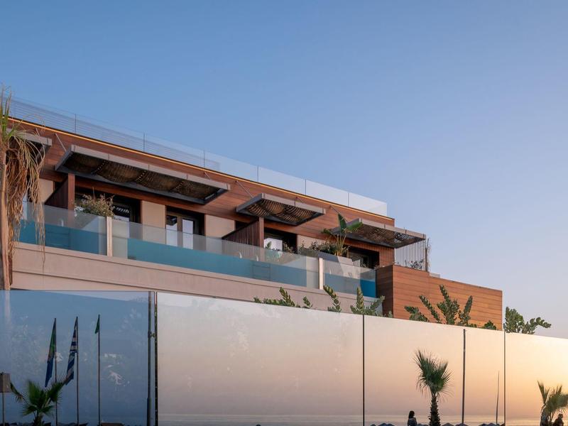 Nowoczesny taras z szklaną balustradą i roślinami o zachodzie słońca.