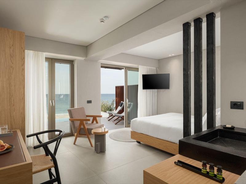 Nowoczesny pokój hotelowy z łóżkiem, miejscem do siedzenia i balkonem z widokiem na morze.