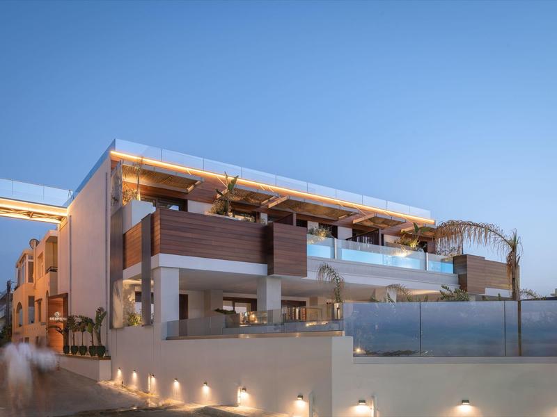 Nowoczesny budynek hotelowy o zmierzchu z oświetlonym tarasem i strefą basenową.