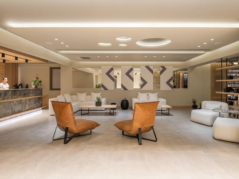 Nowoczesne, jasne lobby hotelowe z stylowymi fotelami i recepcją o kamiennej fakturze.