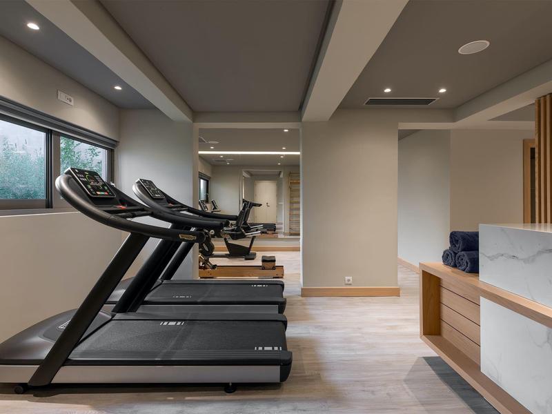 Nowoczesna siłownia z bieżniami i dużym lustrem w hotelu.