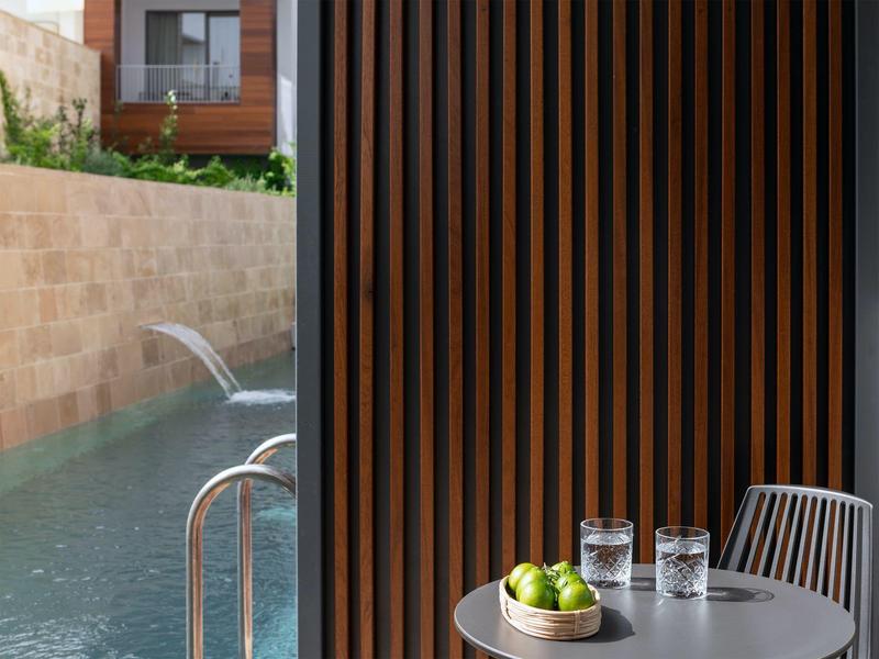 Nowoczesny basen z fontanną wodną obok drewnianych paneli i krzeseł.