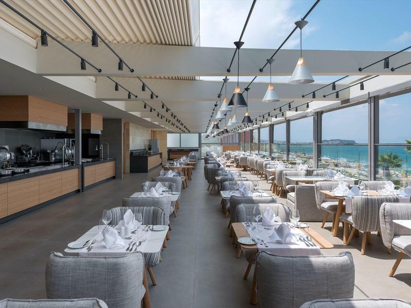 Nowoczesna restauracja z widokiem na morze i elegancko nakrytymi stołami.
