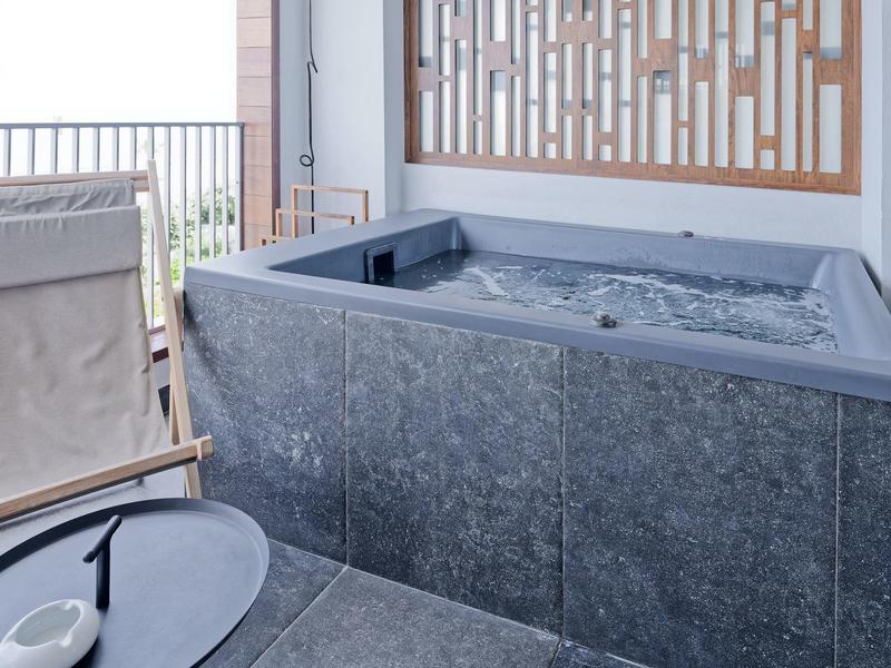 Nowoczesny jacuzzi na tarasie z szarymi płytkami i drewnianą osłoną.