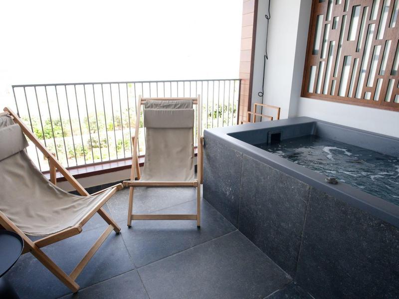 Balkon z dwoma leżakami i dużą wanną z hydromasażem z widokiem na zewnątrz.