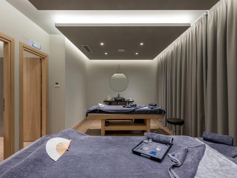 Nowoczesny pokój do masażu z dwoma stołami, uspokajającym wystrojem i miękkim oświetleniem.