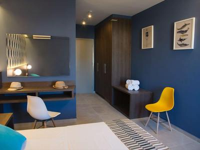 Camera d'albergo moderna con pareti blu, due sedie e una scrivania.