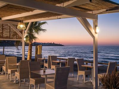 Ristorante all'aperto con vista sul mare al tramonto in un hotel sulla spiaggia.