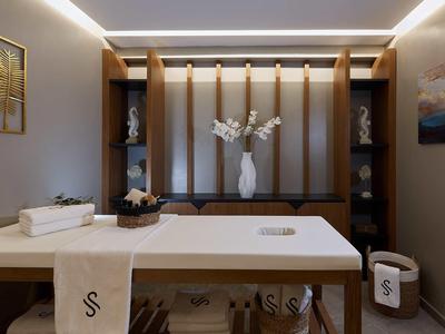 Nowoczesny pokój wellness z łóżkiem do masażu i elementami dekoracyjnymi.