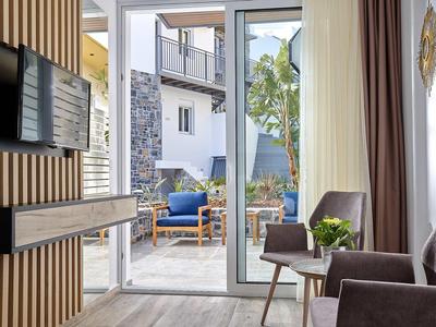 Nowoczesna część wypoczynkowa pokoju hotelowego z dostępem do tarasu i mebli ogrodowych.