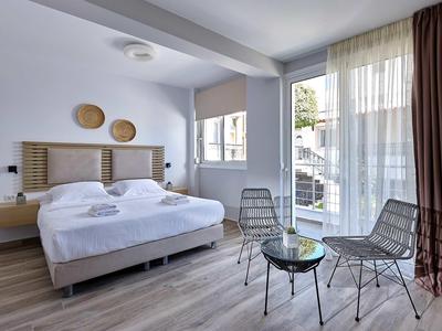 Nowoczesny pokój hotelowy z łóżkiem podwójnym, dwoma krzesłami i szklanym stołem przy oknie od podłogi do sufitu.