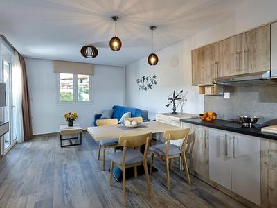 Nowocześnie urządzony salon z jadalnią, meble drewniane i niebieska sofa w jasnym pomieszczeniu.