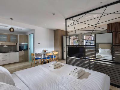 Nowoczesny pokój hotelowy z łóżkiem podwójnym, jadalnią i otwartą aneksem kuchennym.