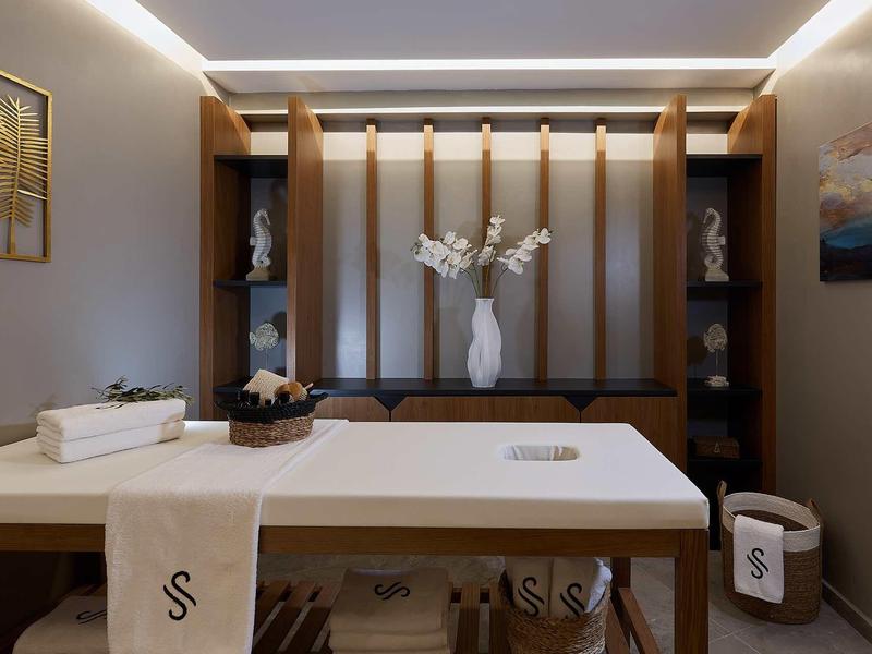 Nowoczesny pokój wellness z łóżkiem do masażu i elementami dekoracyjnymi.