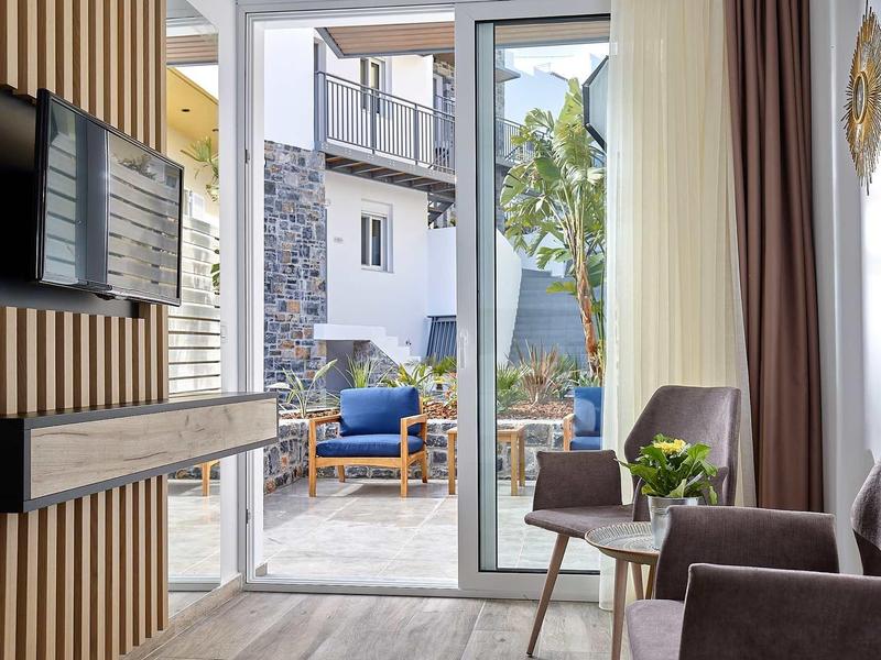 Nowoczesna część wypoczynkowa pokoju hotelowego z dostępem do tarasu i mebli ogrodowych.