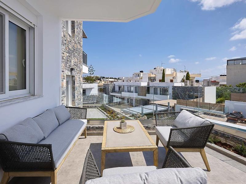 Nowoczesny taras z meblami wypoczynkowymi i widokiem na okoliczne budynki pod czystym niebem.