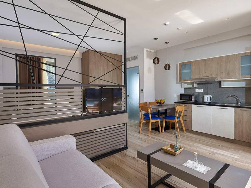 Nowocześnie urządzone salon z otwartą kuchnią i jadalnią w jasnych kolorach.