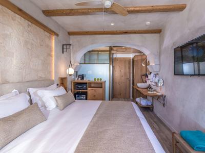 Gemütliches Schlafzimmer mit Doppelbett, hellem Holzmöbeln und offenem Badezimmerhintergrund.