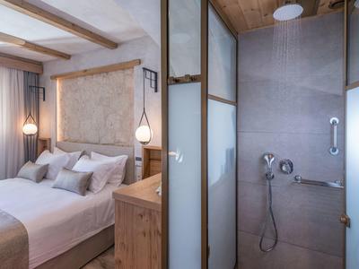 Gemütliches Schlafzimmer mit Doppelbett und angrenzendem modernen Duschbad mit Glaswand.