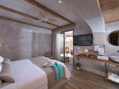 Helles, modernes Schlafzimmer mit Holzbalken, großem Bett, Holzmöbeln und offenem Fenster zur Terrasse.