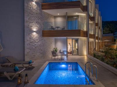 Modern hotel pool at night with illuminated water and adjacent balconies.
