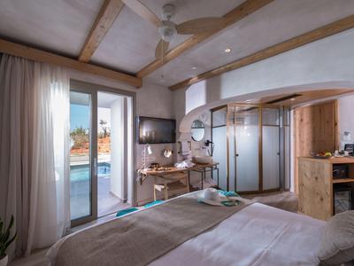 Modern hotel room with bed, desk, and terrace overlooking the sea.