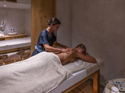 Eine entspannte Massage-Szene in einem ruhigen, warm beleuchteten Raum mit Holzmöbeln.
