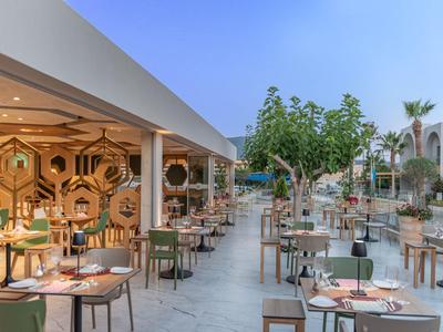 Elegant buitenrestaurant met tafels en moderne zitplaatsen onder bomen.