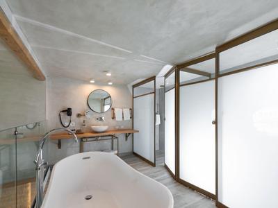 Modernes Badezimmer mit freistehender Badewanne, Holzwaschtisch und satinierter Glasabtrennung.