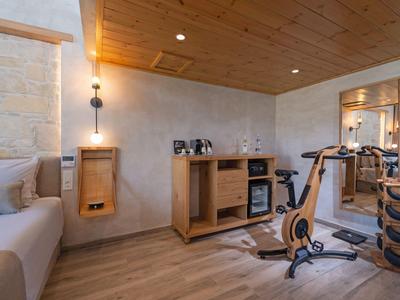 Modern hotel gym with wooden ceiling, dumbbells, exercise bike, and cozy lounge area.