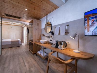 Modernes Hotelzimmer mit Holzmöbeln, Schreibtisch, Waschbecken und Blick auf ein helles Schlafzimmer.