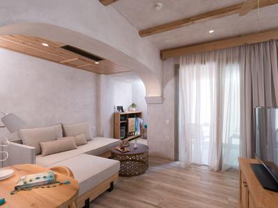 Bright living room with white sofa, wooden beams, and large windows with curtains.