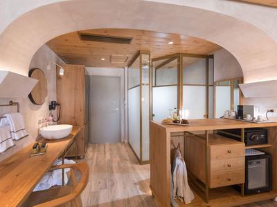 Modern bathroom with wooden ceiling, sink, mirrors, and open storage with minibar.