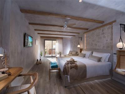 Helles Schlafzimmer mit Holzdecke, großem Bett, Schreibtisch, Stuhl und Zugang zu Terrasse.
