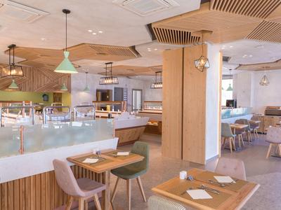 Helles Restaurant mit Holzmöbeln, Pastellstühlen und moderner Deckenbeleuchtung.