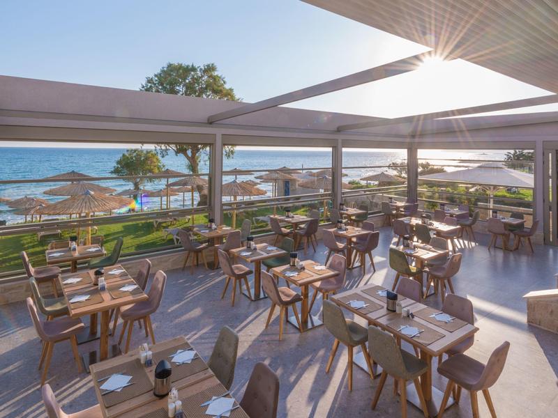 Terras van een restaurant met uitzicht op het strand en de zee op een zonnige dag.