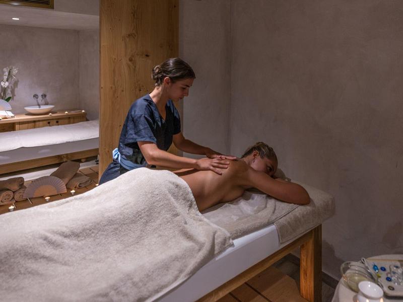 Een man krijgt een rugmassage in een rustige spakamer met houten accenten en zacht licht.