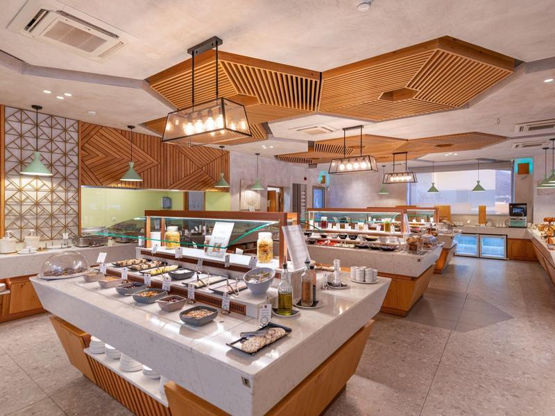 Ruime buffetruimte met diverse voedselstations en moderne houten plafondaccenten.