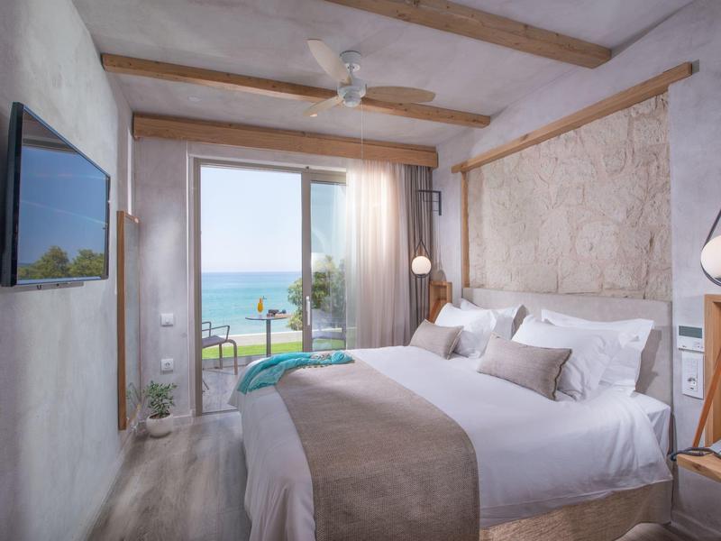 Gezellige slaapkamer met tweepersoonsbed, uitzicht op zee en moderne inrichting met houten accenten.