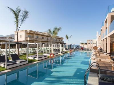 Moderner Hotelpool mit Liegestühlen und Palmen unter klarem Himmel.