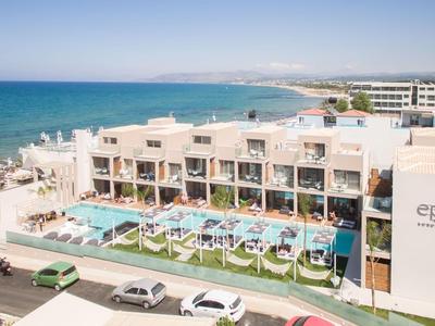Moderner Hotelkomplex am Meer mit Pool, Sonnenschirmen und direktem Strandzugang.